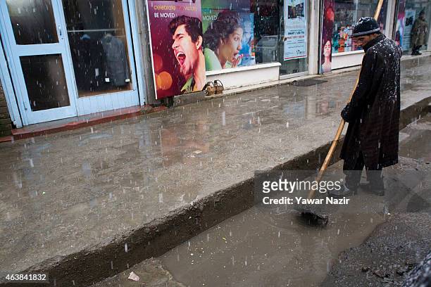 Kashmiri employee cleans a drain manually in the city centre during fresh snowfall on February 19, 2015 in Srinagar, Indian Administered Kashmir,...