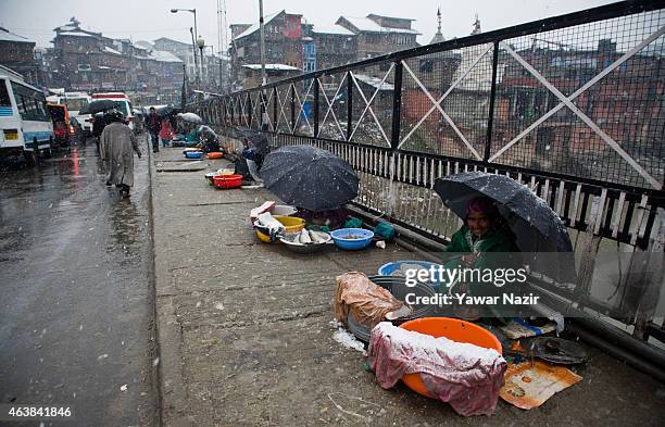 Kashmiri fisher women sell fish as they wait for the customers amid snow flakes on February 19, 2015 in Srinagar, Indian Administered Kashmir, India....