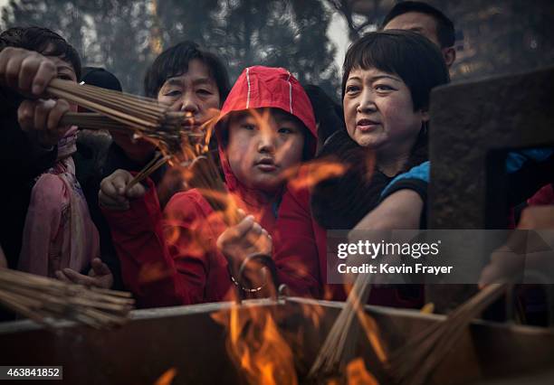 Chinese worshippers light incense while praying at the Yonghegong Lama Temple during celebrations for the Lunar New Year February 19, 2015 in...