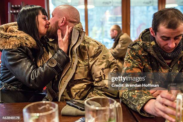 Vika kisses her friend Kolya as fellow soldier Sergei drinks a beer at a local pizza restaurant after their unit withdrew from Debaltseve on February...