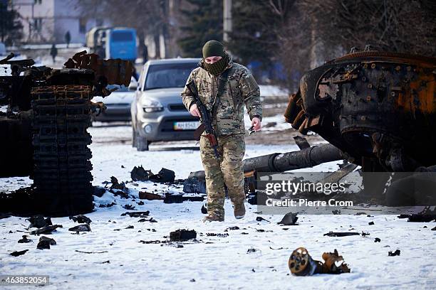 Pro-Russian rebel looks at the remains of a Ukrainian tank as people from the ministry for civil defense and emergencies of the 'Donetsk People's...