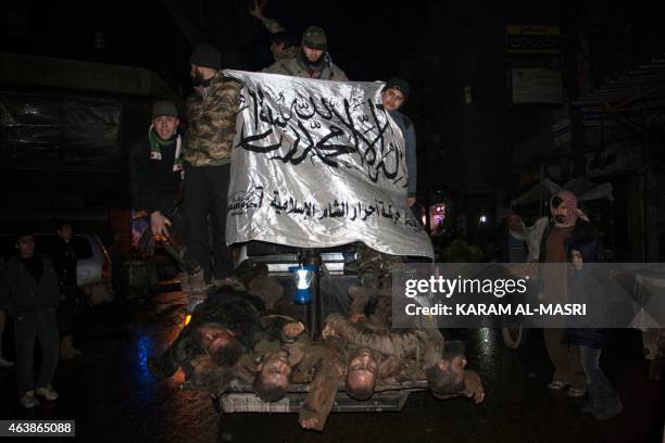 Opposition fighters, wave the flag of Ahrar al-Sham brigade, as they parade in the northern Syrian city of Aleppo on February 19, 2015 the bodies of...