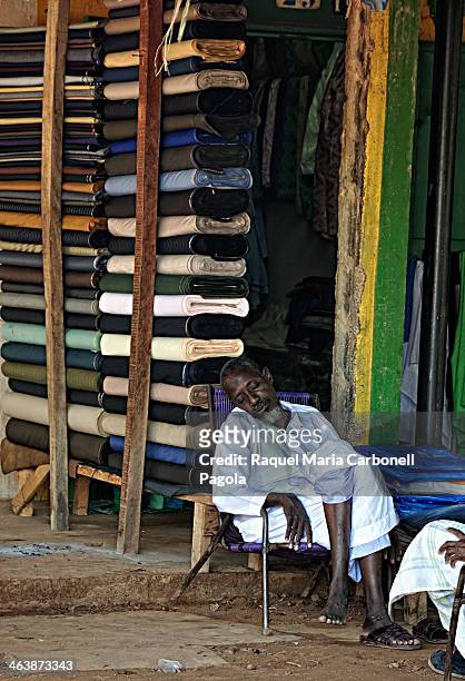 Portrait of a tailor sleeping at his textile store´s doorway.