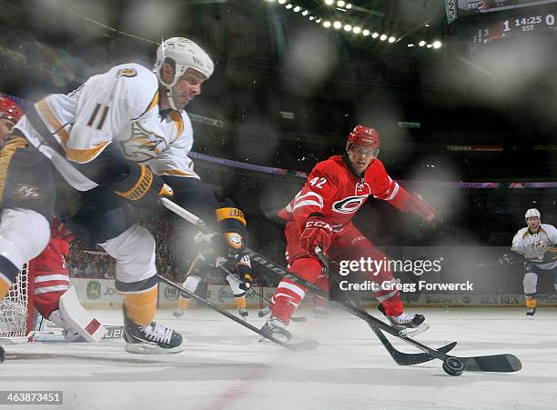 Brett Sutter of the Carolina Hurricanes battles for a loose puck with David Legwand of the Nashville Predators during their NHL game at PNC Arena on...