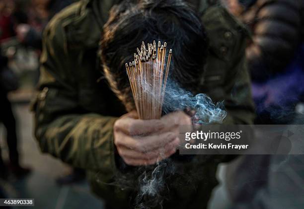 Chinese worshipper holds incense while praying with others at the Yonghegong Lama Temple during celebrations for the Lunar New Year February 19, 2015...