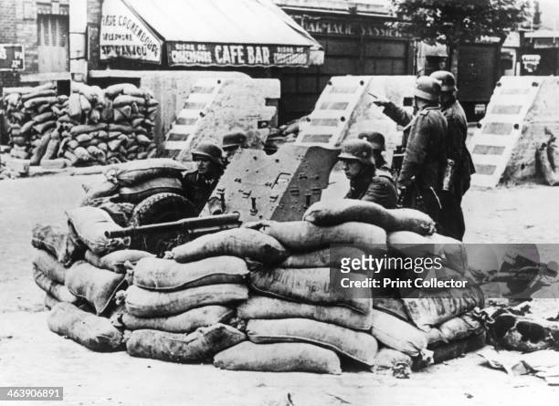 German soldiers with captured French barricade, near Paris, June 1940. The first German troops entered Paris, which had been declared an open city by...