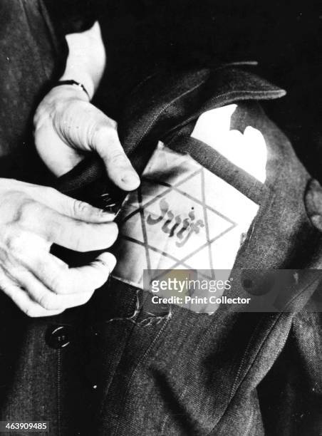 Sewing the yellow star identifying a Jew onto a jacket, German-occupied Paris, 1942. Life for French Jews became increasingly oppressive under Nazi...