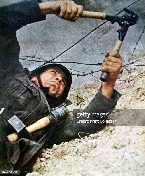German soldier cutting through barbedwire during an assalt, 1942. A print from Signal, April 1942. Signal was a magazine published by the German...