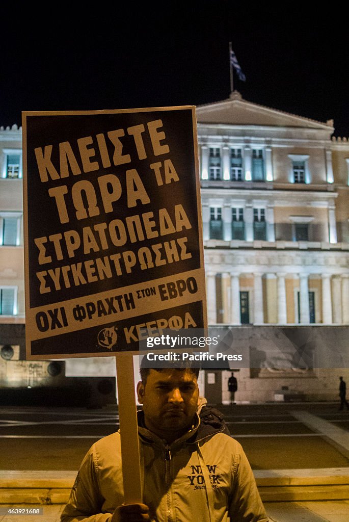 An immigrant poses with a placard in front of the Greek...