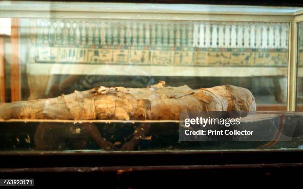 Mummy wrapped in bandages and lying on the base of a coffin, Ancient Egyptian. From the Cairo Museum, Egypt.