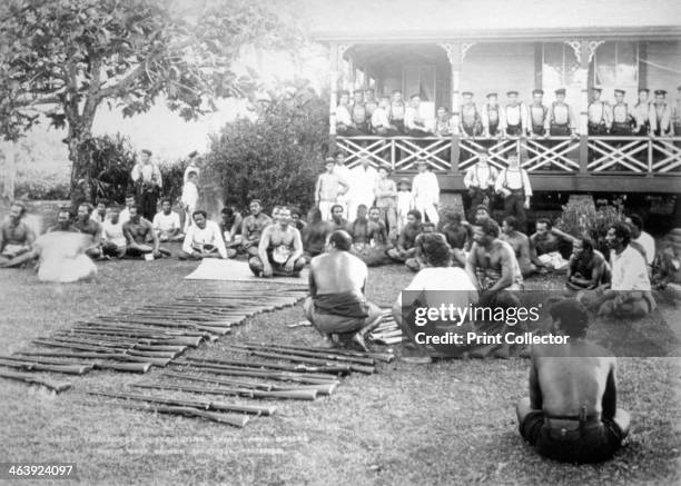 Tamasese distributing arms, Apia, Samoa, 1899. Samoan Civil War 1898-1899. A view showing Tamasese sitting on the ground, with rifles in front of...