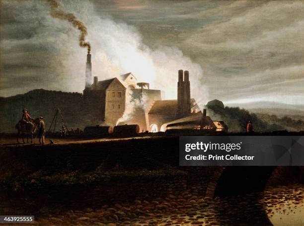 Industrial landscape, Wales, 19th century. An ironworks at night, the blast furnace in the centre.