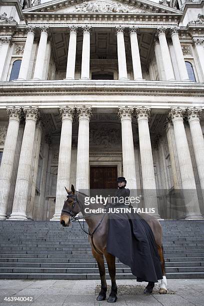 Model sitting on a horse wearing a black top hat, veil, jacket and trailing skirt by Sarah Burton for Alexander McQueen is pictured outside St Paul's...