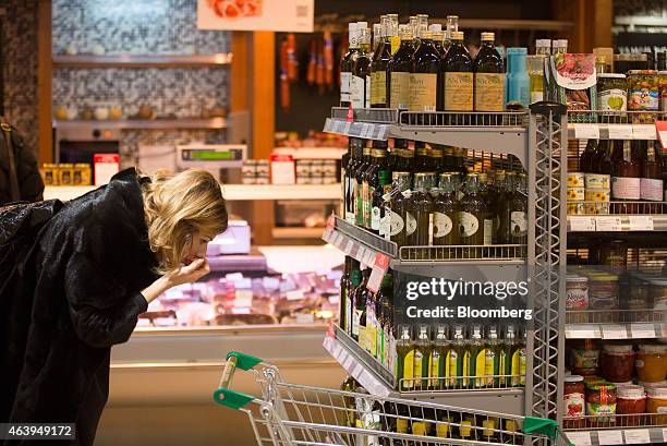 Customer inspects a display of olive oil for sale on the shelves of an Azbuka Vkusa OOO, which translates as "Elements of Taste," supermarket at the...