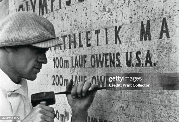 Berlin Olympics, 1936. Jesse Owens' name being inscribed on the monument listing gold medal winners. A print from Olympia 1936, Die Olympischen...