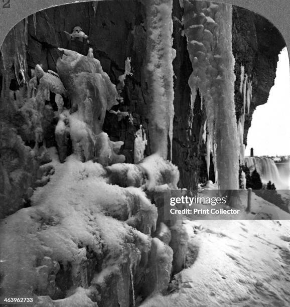 Niagara Falls, New York, USA. In the icy grip of winter, huge icicles and frozen spray below the cataract. Stereoscopic card detail.