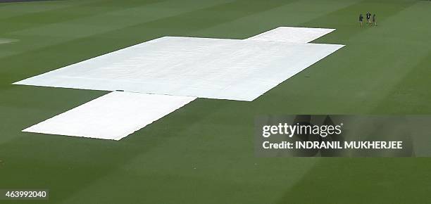 Ground staff walk across the field amidst rain from Tropical Cyclone Marcia ahead of the 2015 Cricket World Cup match between Australia and...