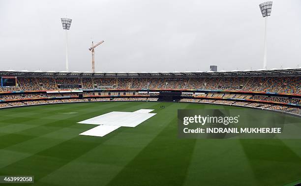 Ground staff walk across the field amidst rain from Tropical Cyclone Marcia ahead of the 2015 Cricket World Cup match between Australia and...