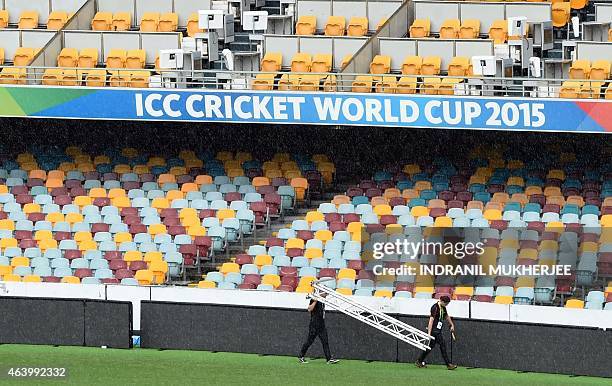 Staff carry a ladder across the field amidst rain from Tropical Cyclone Marcia ahead of the 2015 Cricket World Cup Pool A match between Australia and...