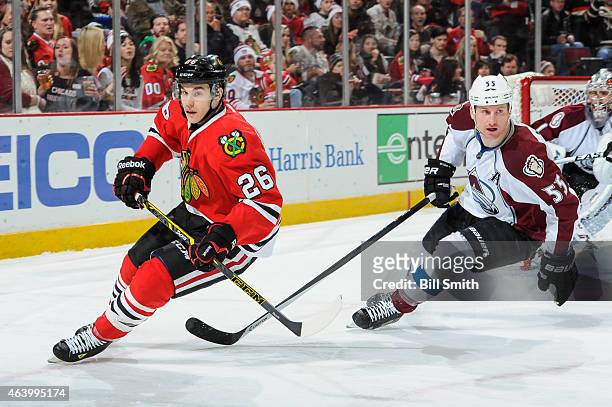 Kyle Cumiskey of the Chicago Blackhawks and Cody McLeod of the Colorado Avalanche skate around the boards during the NHL game at the United Center on...