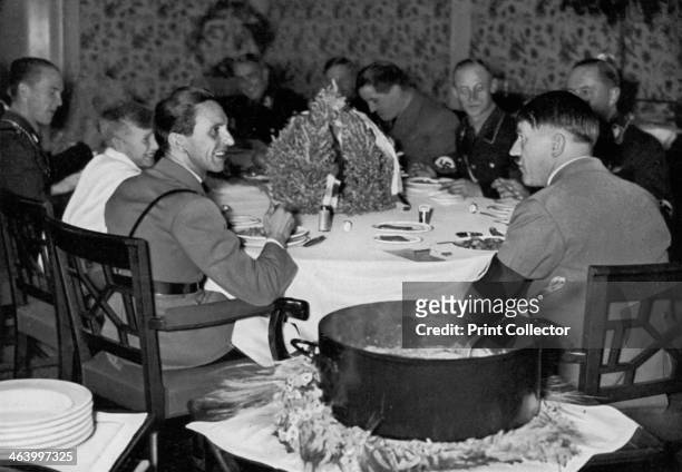 'Stew with the German Chancellor', 1936. Nazi leader Adolf Hitler eating dinner with colleagues, including Reich Propaganda Minister Joseph Goebbels...