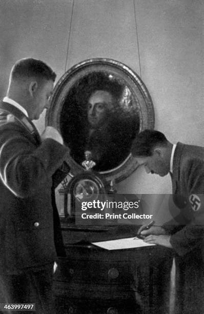 Adolf Hitler and Viktor Lutze, 1936. German Nazi leader Hitler signing a document watched by Lutze , head of the Sturmabteilung . Behind the two men...