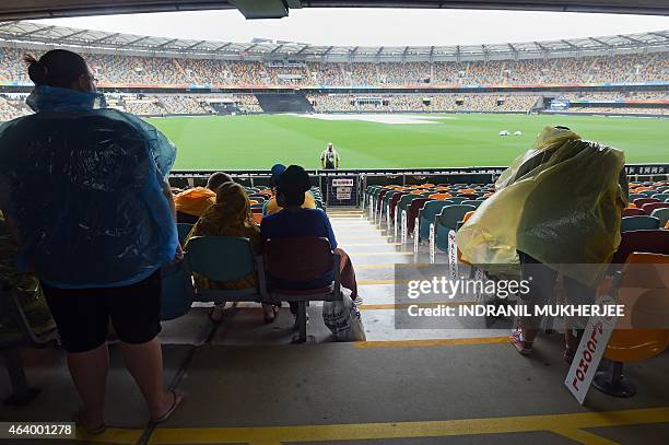 Spectators wearing protective rain gear wait in the stands inside the grounds amidst a drizzle from Cyclone Marcia ahead of the 2015 Cricket World...