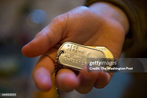 Part of this image was altered to obscure personal identification. VIRGINIA BEACH, VA Ethan Prusinski holds dog tags belonging to his late...