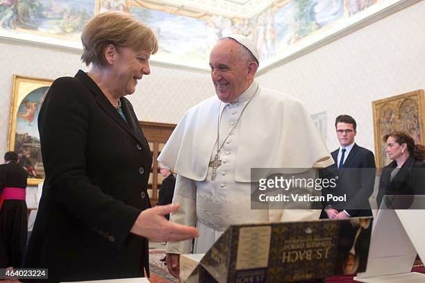 Pope Francis exchanges gifts with Chancellor of Germany Angela Merkel during a private audience at the Apostolic Palace on February 21, 2015 in...