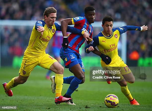 Wilfried Zaha of Crystal Palace takes on Alexis Sanchez and Nacho Monreal of Arsenal during the Barclays Premier League match between Crystal Palace...