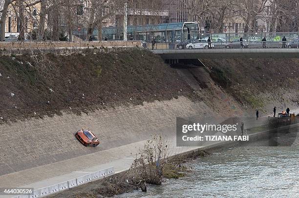 Crew members stand while a Jaguar C-X75 is driven during the shooting of scenes for the 24th James Bond movie 'Spectre' in Rome on February 21, 2015....