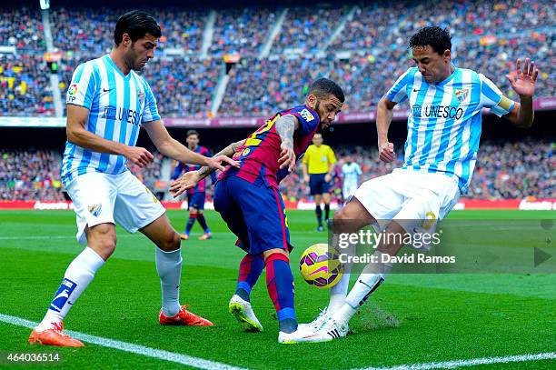 Dani Alves of FC Barcelona competes for the ball with Welligton Robson and Miguel Torres of Malaga CF during the La Liga match between FC Barcelona...