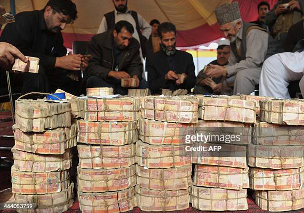 Afghan officials count and adjust wads of Afghan currency before setting the notes on fire in Jalalabad, Nangarhar province, on January 20, 2014....