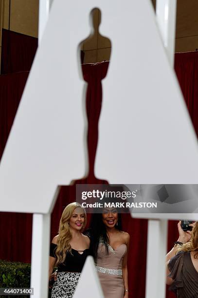 People pose for photos on the red carpet area outside the Dolby Theatre as preparations are underway for the 87th annual Academy Awards in Hollywood,...