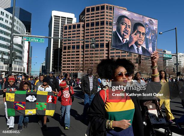 Joining a large crowd as they make their way on to Broadway, Destiney Scott of Denver carries a sign honoring Dr. Martin Luther King, Jr. And Malcolm...