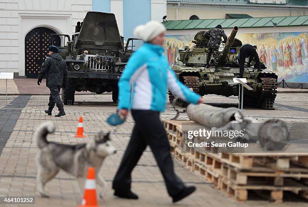 Woman walks her dog past a rocket launcher truck, a heavy tank and the remains of a missle that are part of an exhibition the Ukrainian government...