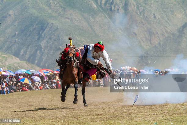 Khampa horseman practice shooting small pieces of paper with flint lock guns from the back of a galloping horse at the Yushu Horse Racing Festival in...