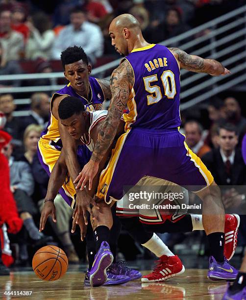 Jimmy Butler of the Chicago Bulls tries to get between Manny Harris and Robert Sacre of the Los Angeles Lakers at the United Center on January 20,...