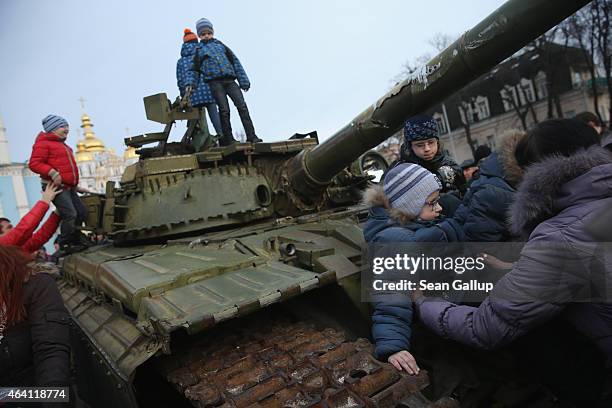 Children climb onto a heavy tank that is part of an exhibition of weapons, drones, documents and other materials the Ukrainian government claims it...