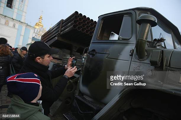 People look at a missile launcher truck that is part of an exhibition of weapons, drones, documents and other materials the Ukrainian government...