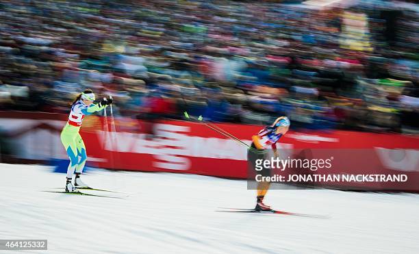 Picture taken with long exposure shows Team Germany's Nicole Fessel and team Slovenia's Katja Visnar as they compete during the ladies cross-country...