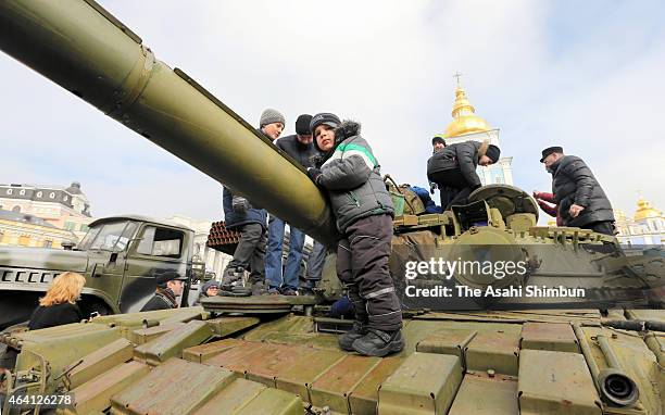 Children stand on top of a heavy tank that is part of an exhibition of weapons, drones, documents and other materials the Ukrainian government claims...