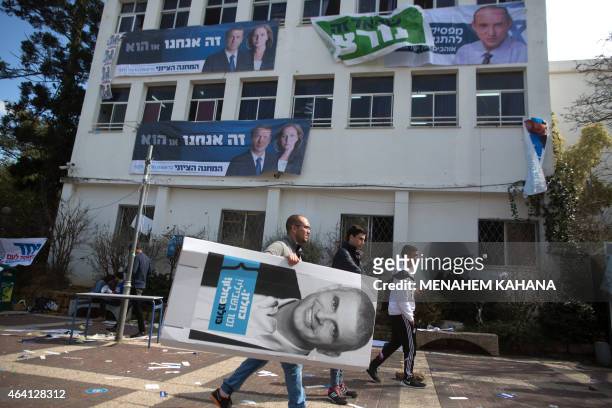 An Israeli student of the Blich high school carries a poster of former Likud minister Moshe Kahlon as he walks past posters of Tzipi Livni and Isaac...