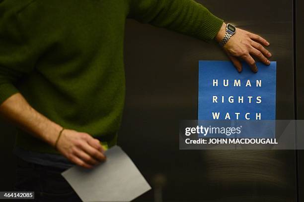 Man puts a logo of US-based rights group Human Rights Watch on the wall as he prepares the room before their press conference to release their annual...