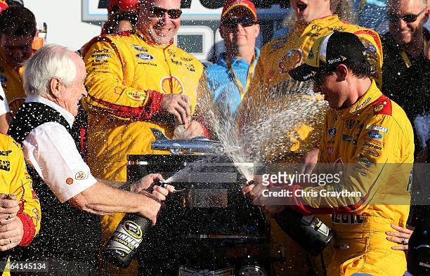 Joey Logano, driver of the Shell Pennzoil Ford, right, and team owner Roger Penske celebrate in victory lane with champagne after winning the NASCAR...