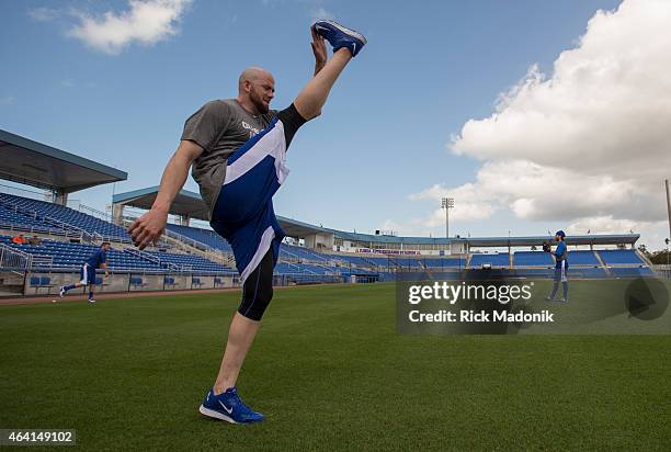 Pitcher Steve Delabar does a high kick as he loosens up. In the background, catcher Josh Thole and pitcher RA Dickey get their arms in throwing...