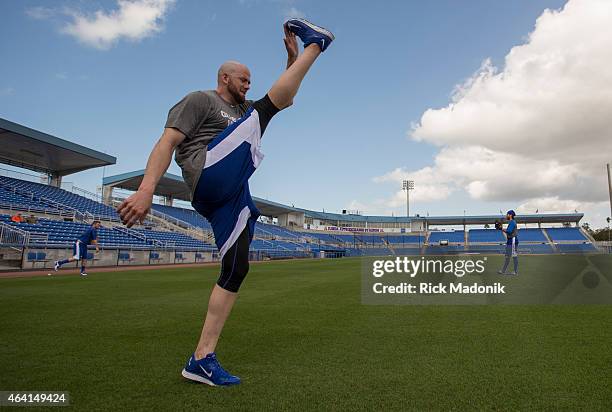 Pitcher Steve Delabar does a high kick as he loosens up. In the background, catcher Josh Thole and pitcher RA Dickey get their arms in throwing...