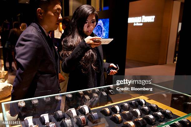 Visitors look at a display of luxury wristwatches manufactured by Audemars Piguet at the Salon International de la Haute Horlogerie watch fair in...