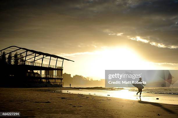 Surfer runs up the beach as the sunset at Snapper Rocks on February 16, 2015 on the Gold Coast, Australia.