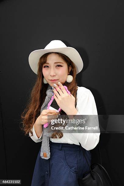 Hayley Hyejin Japanese fashion design student studying at UCA, Epsom holding a Moschino rubber Iphone holder styled as a hand mirror, and wearing...